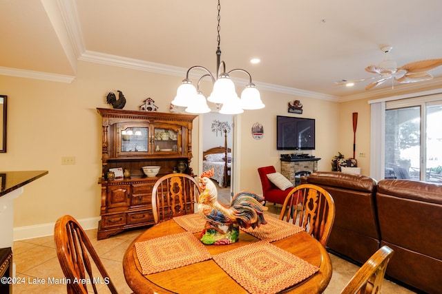 dining area with ceiling fan with notable chandelier, light tile patterned flooring, crown molding, and a fireplace