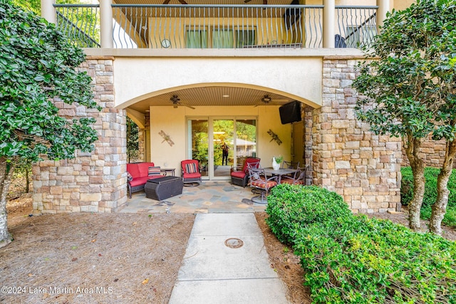 property entrance with ceiling fan, a balcony, a patio, and an outdoor hangout area