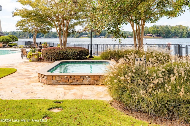 view of swimming pool featuring a jacuzzi, a patio, and a water view