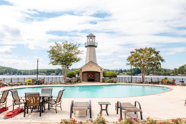 view of swimming pool with a water view, a patio, and an outdoor fireplace