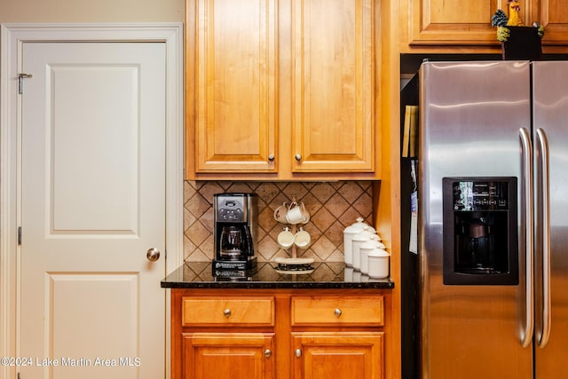 kitchen with decorative backsplash, stainless steel fridge, and dark stone counters