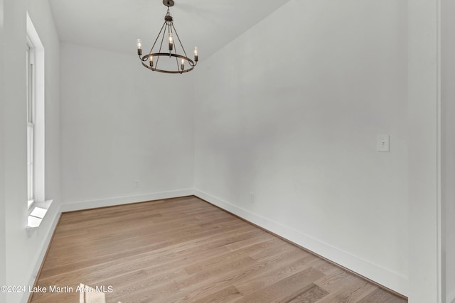 empty room with an inviting chandelier and light hardwood / wood-style flooring