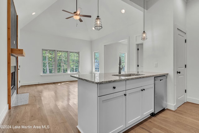 kitchen featuring light wood-type flooring, light stone counters, sink, dishwasher, and white cabinetry