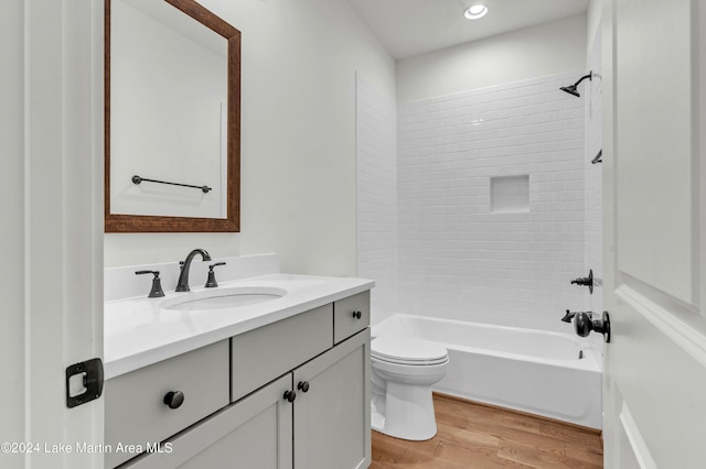 full bathroom featuring hardwood / wood-style floors, vanity, toilet, and tiled shower / bath