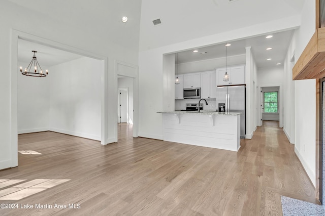 interior space with sink, light hardwood / wood-style flooring, a towering ceiling, and an inviting chandelier