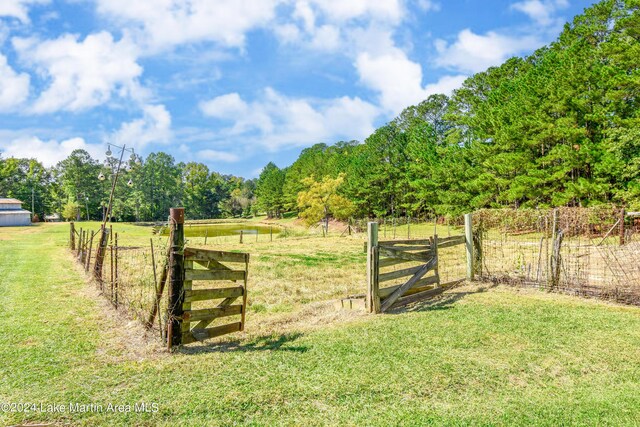 view of gate with a rural view and a lawn