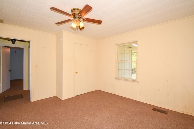 unfurnished bedroom featuring a closet, ceiling fan, crown molding, and carpet