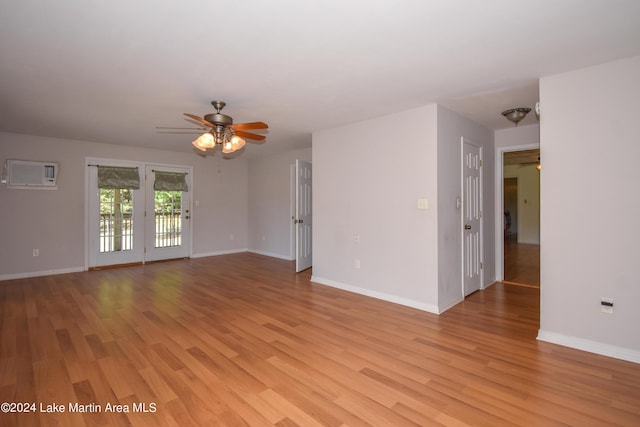 spare room featuring light hardwood / wood-style floors, an AC wall unit, and ceiling fan