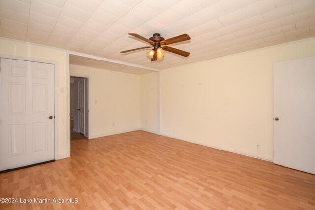 empty room featuring ceiling fan, crown molding, and light wood-type flooring