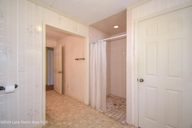 bathroom featuring curtained shower, tile walls, and ornamental molding