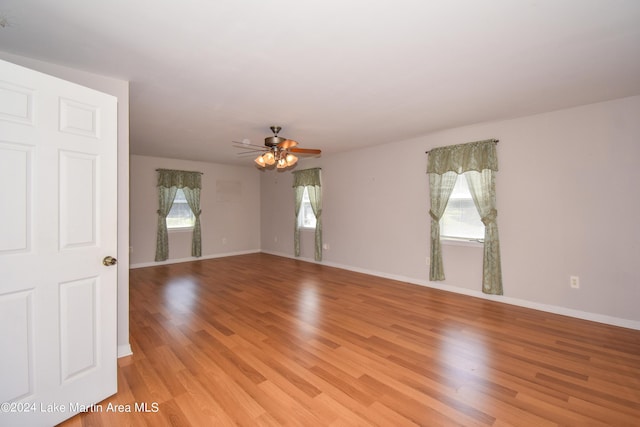 empty room with a wealth of natural light, light hardwood / wood-style flooring, and ceiling fan