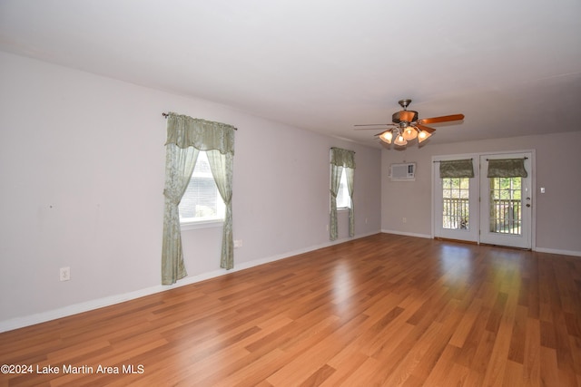 empty room featuring a wall mounted air conditioner, ceiling fan, and light hardwood / wood-style floors