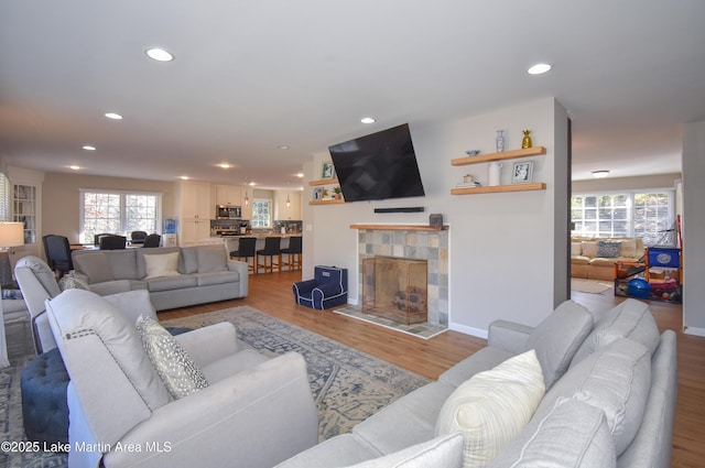 living room featuring a tile fireplace, plenty of natural light, and light hardwood / wood-style floors