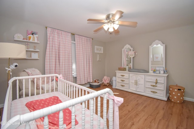 bedroom with ceiling fan, light wood-type flooring, and a crib