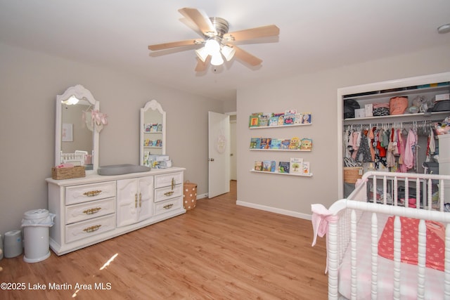 bedroom featuring ceiling fan, light hardwood / wood-style floors, a crib, and a closet