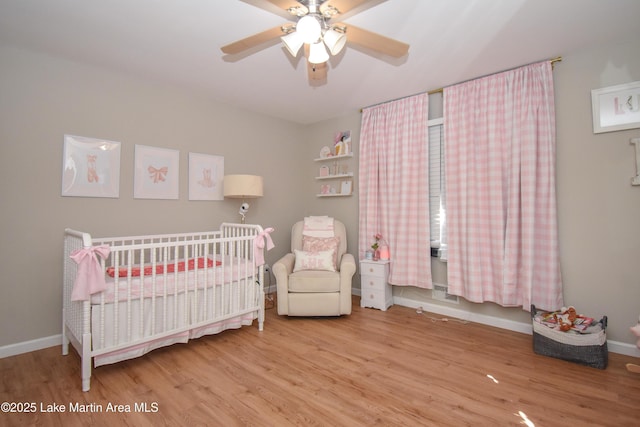 bedroom with ceiling fan, light hardwood / wood-style floors, and a nursery area