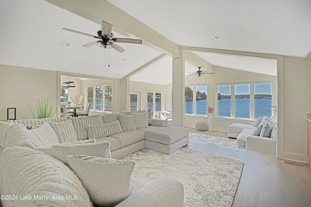 living room with hardwood / wood-style floors, ceiling fan, vaulted ceiling with beams, and a water view