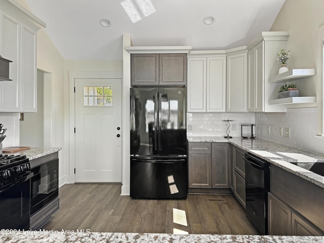 kitchen featuring black appliances, dark hardwood / wood-style floors, and light stone counters