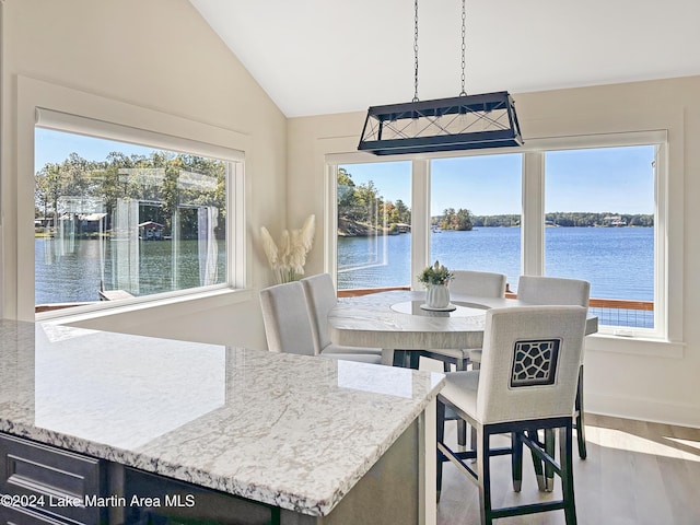 dining area featuring a water view, hardwood / wood-style flooring, and lofted ceiling