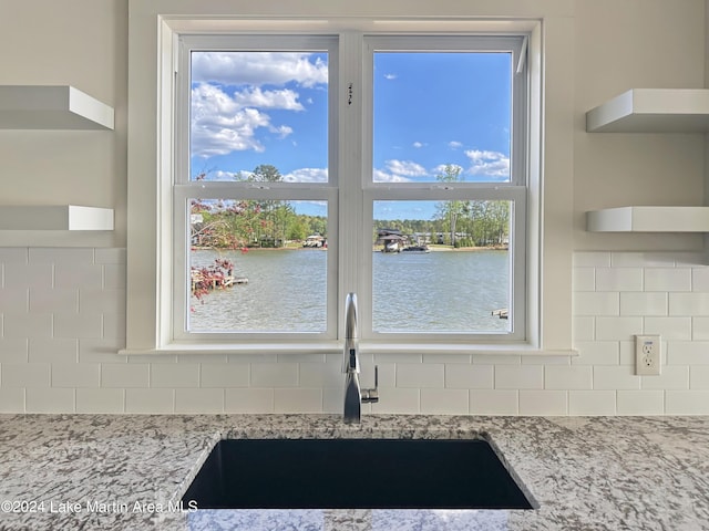 kitchen with a water view, light stone countertops, and sink