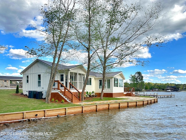 rear view of property featuring a sunroom, cooling unit, and a water view