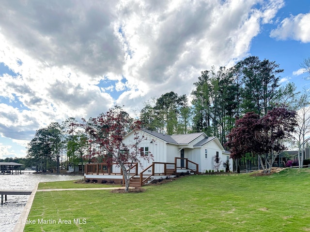 view of front facade with a deck with water view and a front lawn