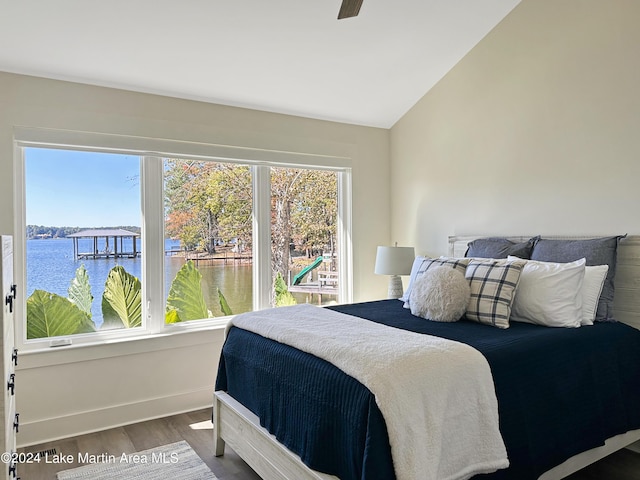 bedroom featuring wood-type flooring, a water view, vaulted ceiling, and ceiling fan