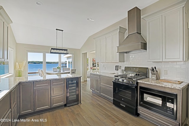 kitchen with lofted ceiling, premium range hood, black appliances, a water view, and wine cooler