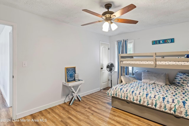 bedroom with ceiling fan, a textured ceiling, and light wood-type flooring