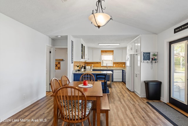 dining area featuring a wealth of natural light, light hardwood / wood-style floors, and vaulted ceiling