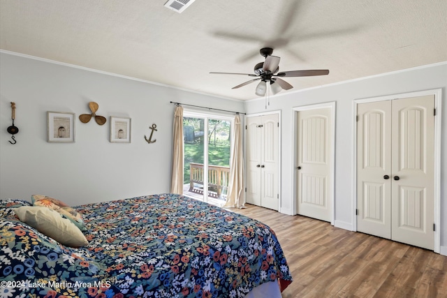 bedroom with access to outside, two closets, ceiling fan, ornamental molding, and wood-type flooring