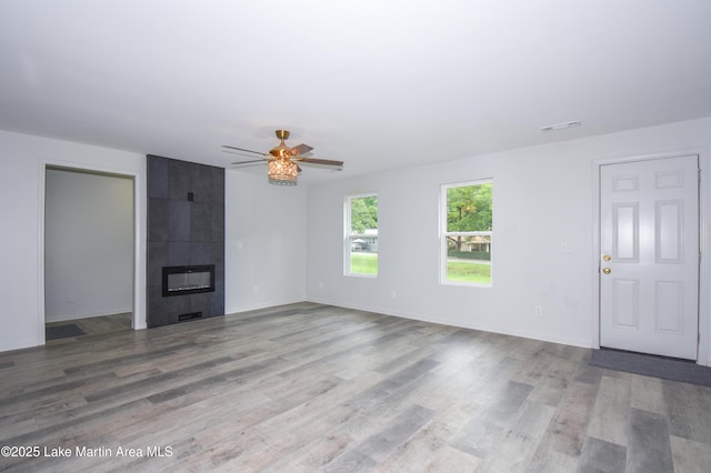 1706 Simpson St, Alexander City, AL 35010 - unfurnished living room with wood finished floors, a ceiling fan, and a tiled fireplace