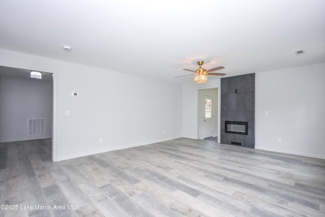 1706 Simpson St, Alexander City, AL 35010 - unfurnished living room with light wood finished floors, a ceiling fan, and a tile fireplace