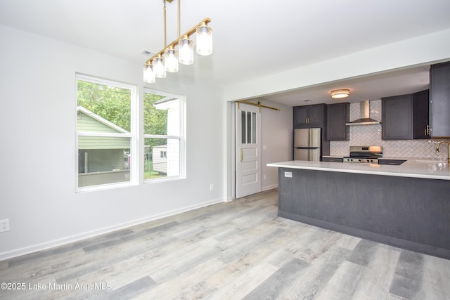 1706 Simpson St, Alexander City, AL 35010 - kitchen featuring appliances with stainless steel finishes, wall chimney range hood, light countertops, tasteful backsplash, and a peninsula