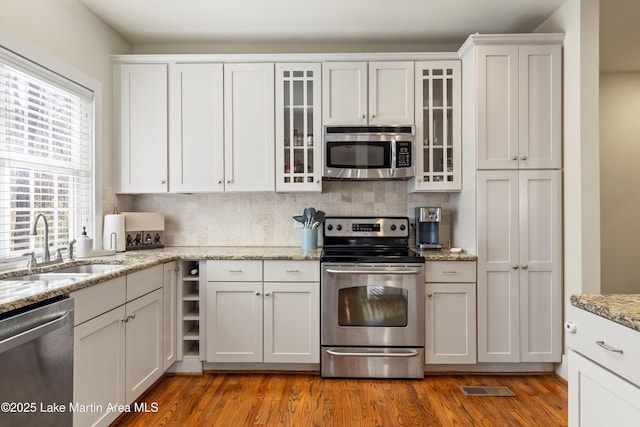 kitchen with stainless steel appliances, backsplash, dark wood-type flooring, white cabinets, and a sink