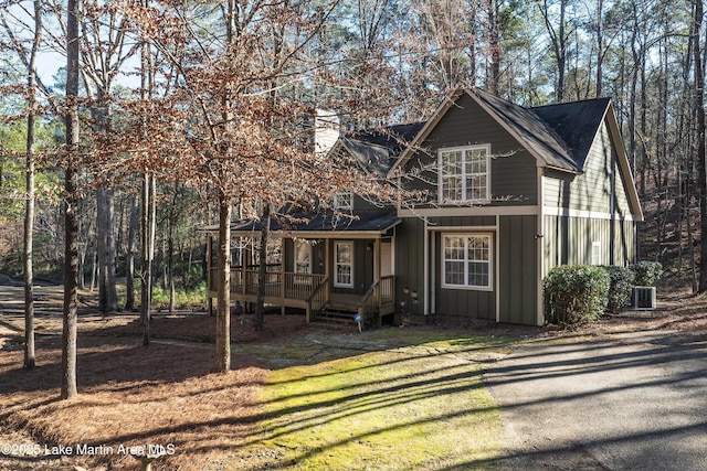 chalet / cabin featuring a front lawn, board and batten siding, a chimney, and cooling unit