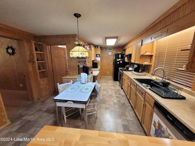 kitchen featuring pendant lighting, wooden walls, sink, and stainless steel appliances