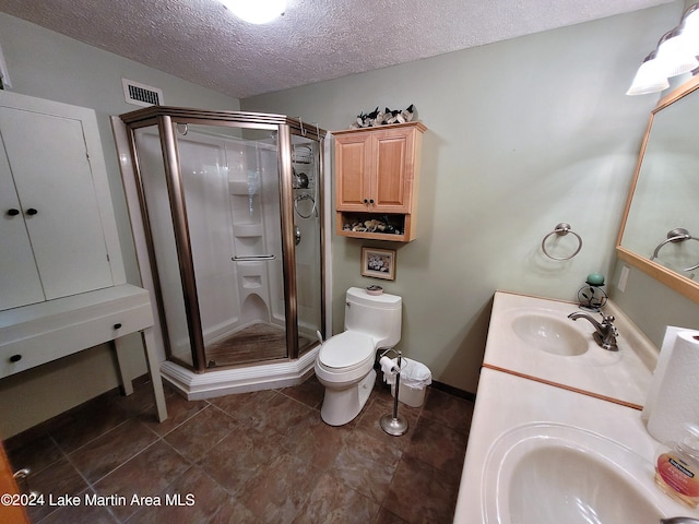 bathroom with vanity, a shower with shower door, a textured ceiling, and toilet