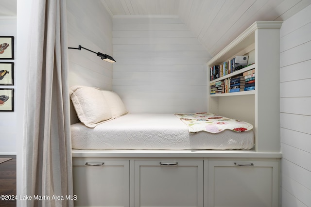 bedroom featuring lofted ceiling and wood walls