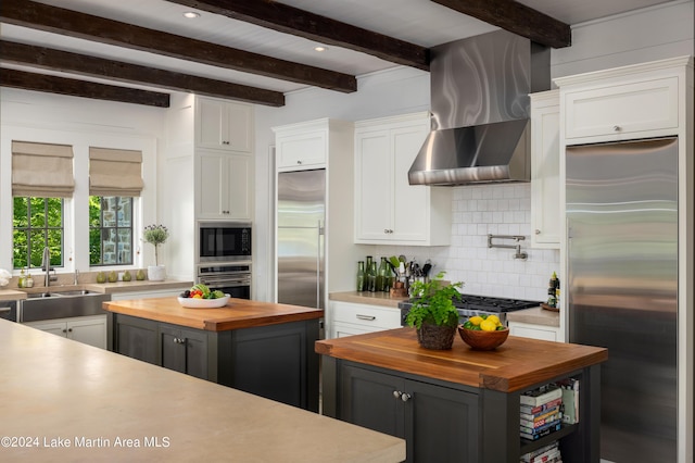 kitchen with built in appliances, white cabinetry, a kitchen island, and butcher block counters