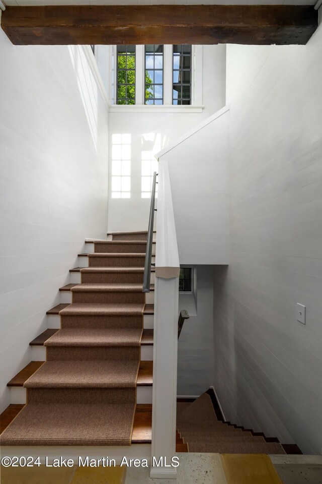 staircase with beam ceiling and a towering ceiling