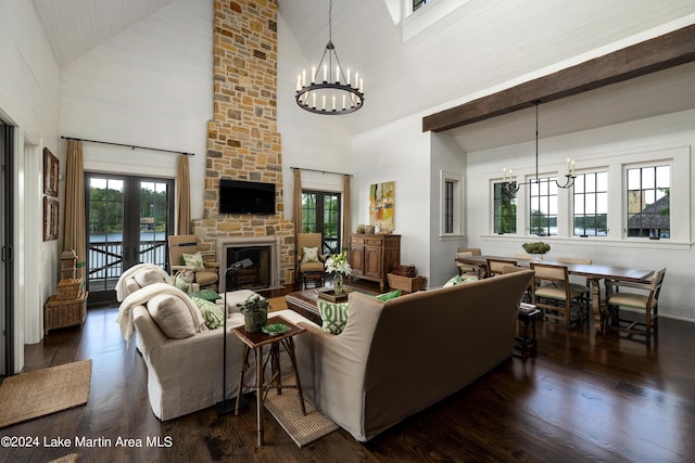 living room with dark wood-type flooring, high vaulted ceiling, an inviting chandelier, french doors, and a stone fireplace