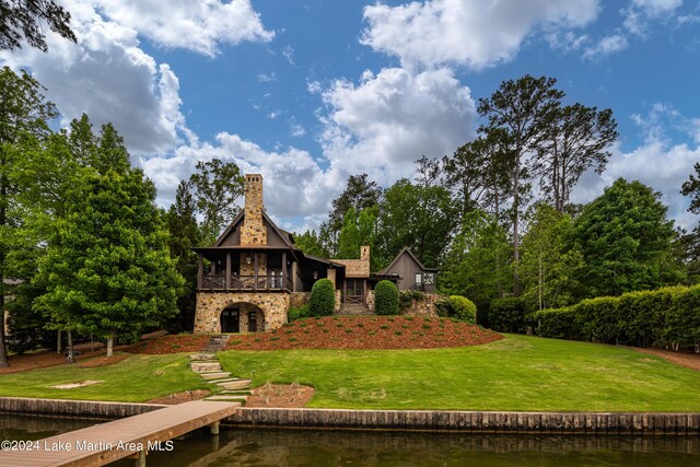 back of property featuring a lawn and a water view