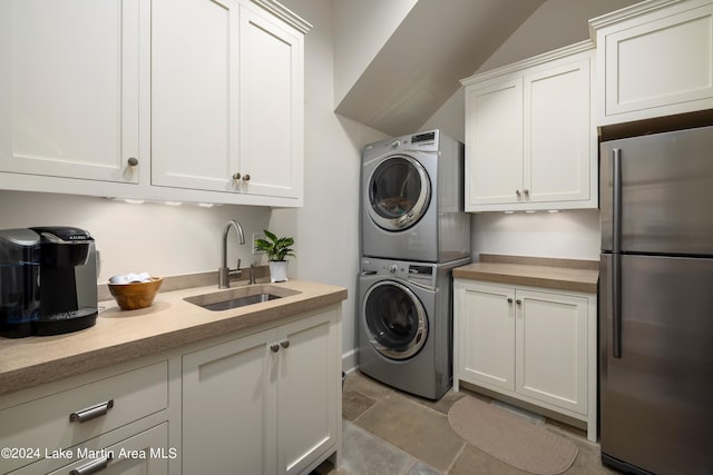 clothes washing area featuring cabinets, stacked washer and dryer, and sink