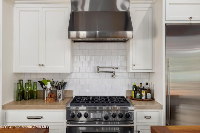 kitchen with white cabinets, wall chimney exhaust hood, and high quality appliances