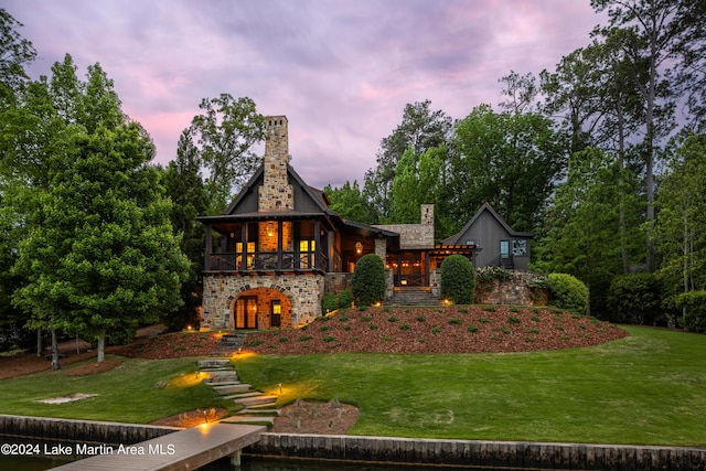 back house at dusk featuring a lawn