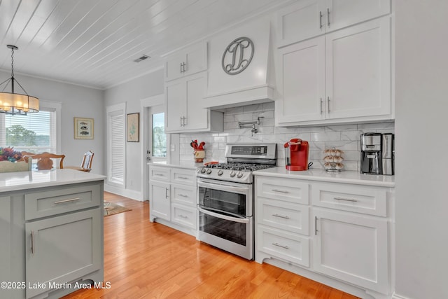 kitchen featuring premium range hood, white cabinetry, decorative light fixtures, double oven range, and backsplash