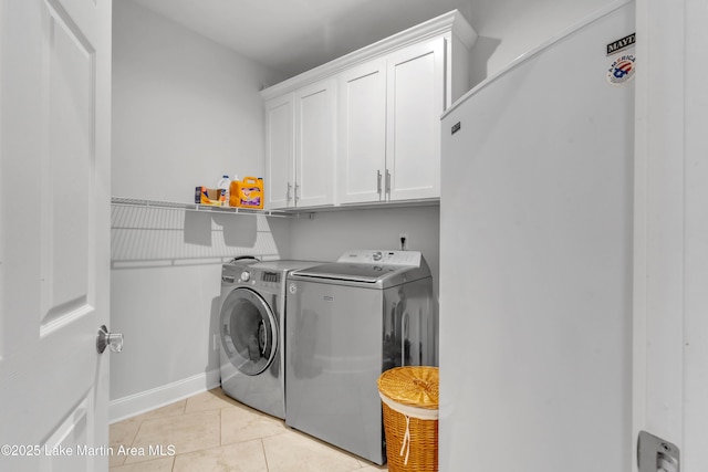 laundry area featuring cabinets, light tile patterned floors, and independent washer and dryer