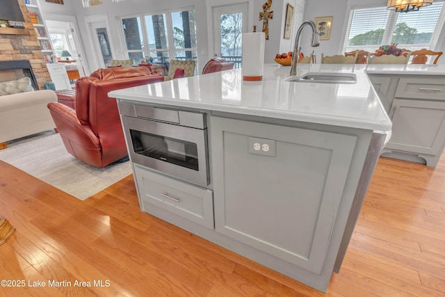 kitchen featuring sink, a wealth of natural light, a fireplace, and a center island with sink