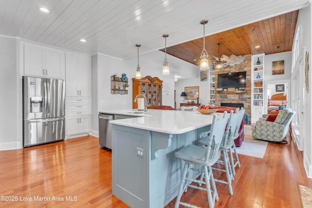 kitchen with pendant lighting, a center island with sink, white cabinets, and appliances with stainless steel finishes